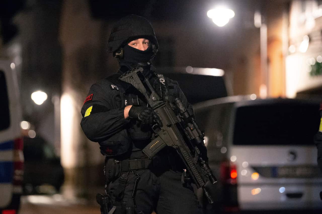 Emergency forces are standing with machine guns in a street near the place where a car drove into a Rose Monday procession.