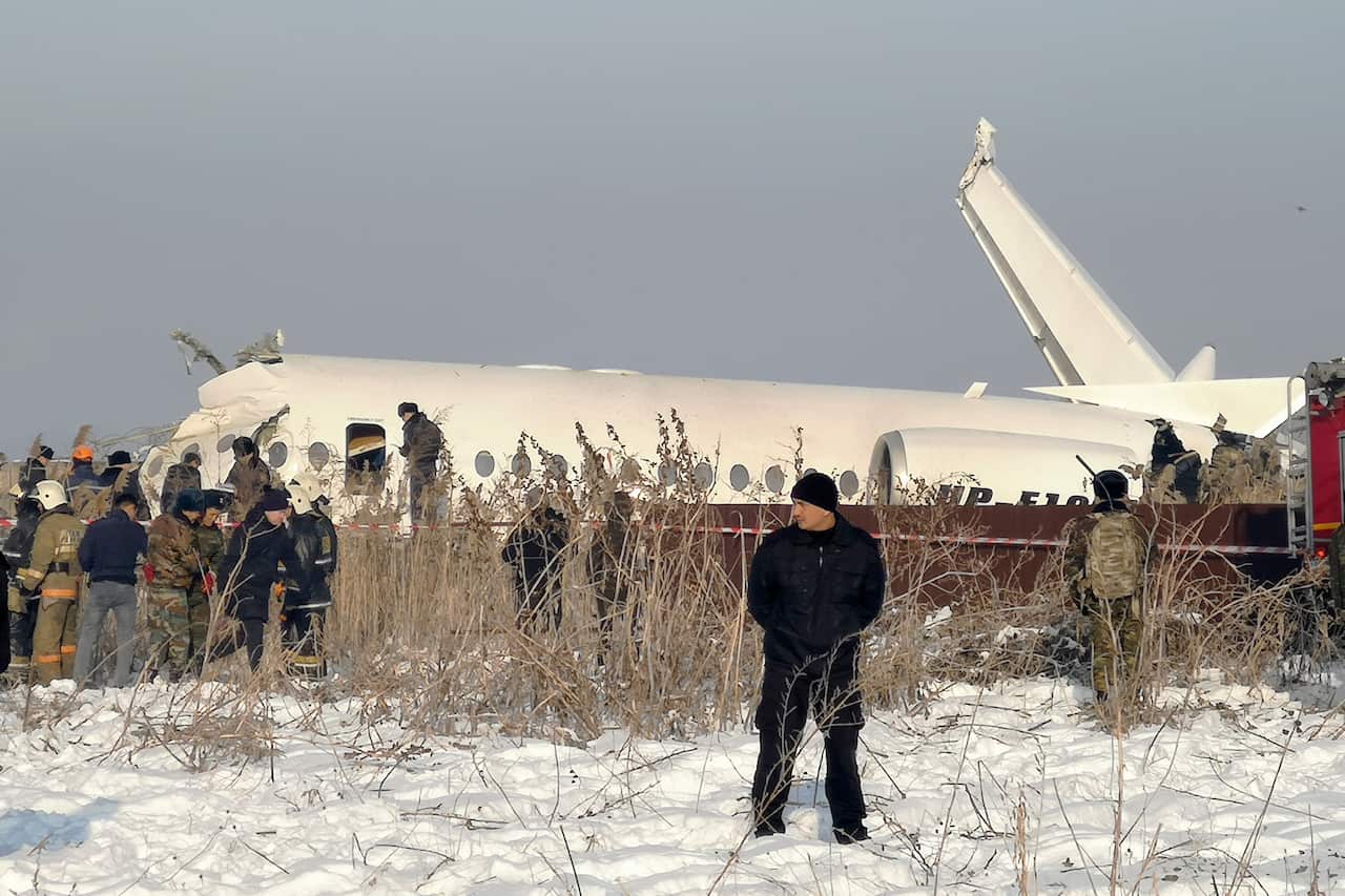 Police stand guard as rescuers work on the side of a plane crash near Almaty International Airport, outside Almaty, Kazakhstan.