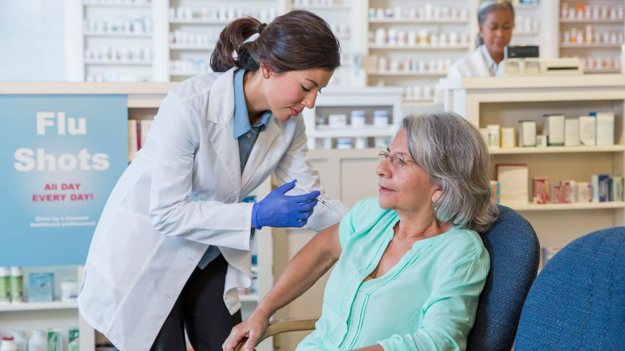 Chemist giving woman flu shot 