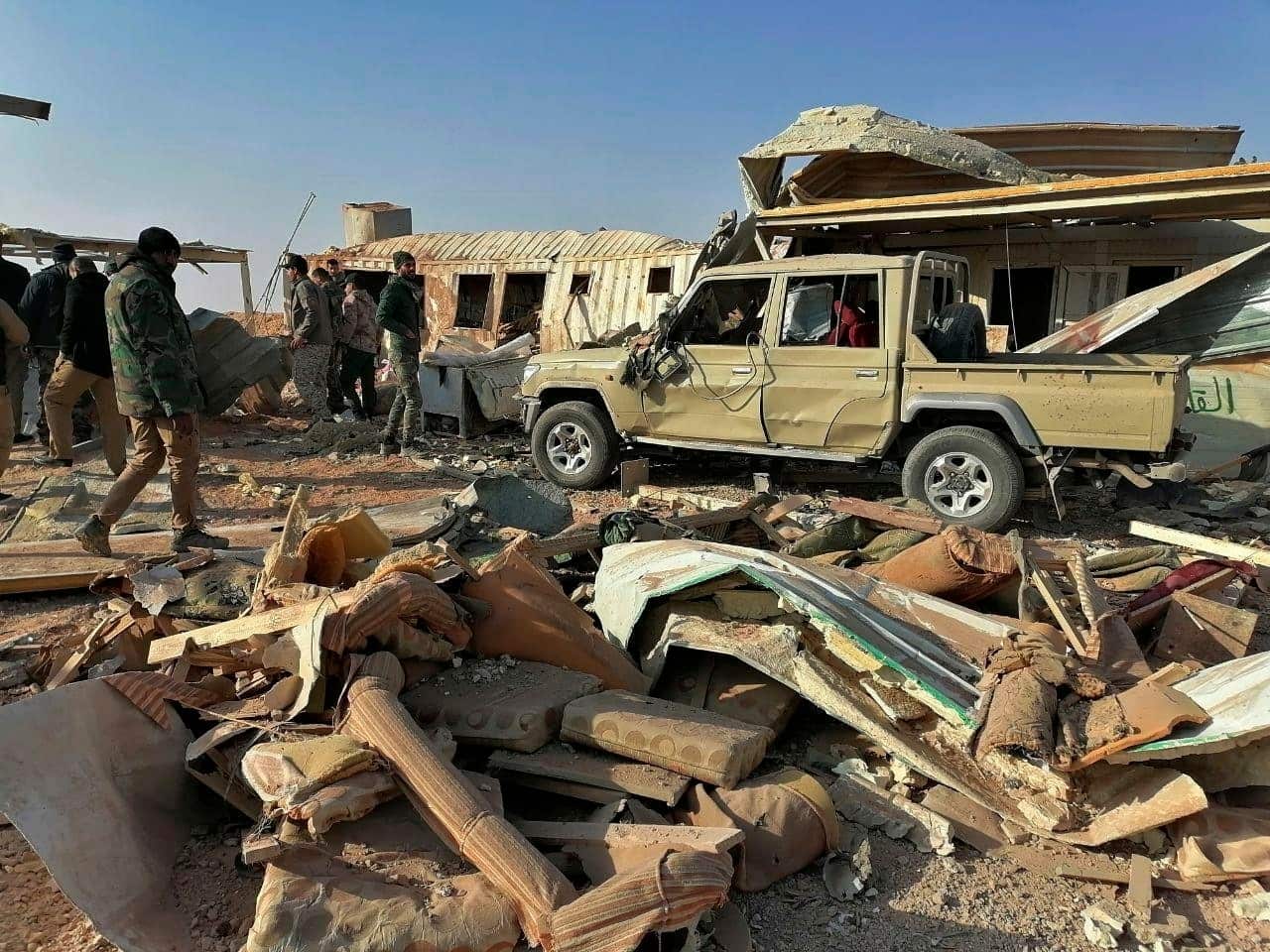 Fighters from the Kataeb Hezbollah inspect the destruction at their headquarters in the aftermath of a US air strike.