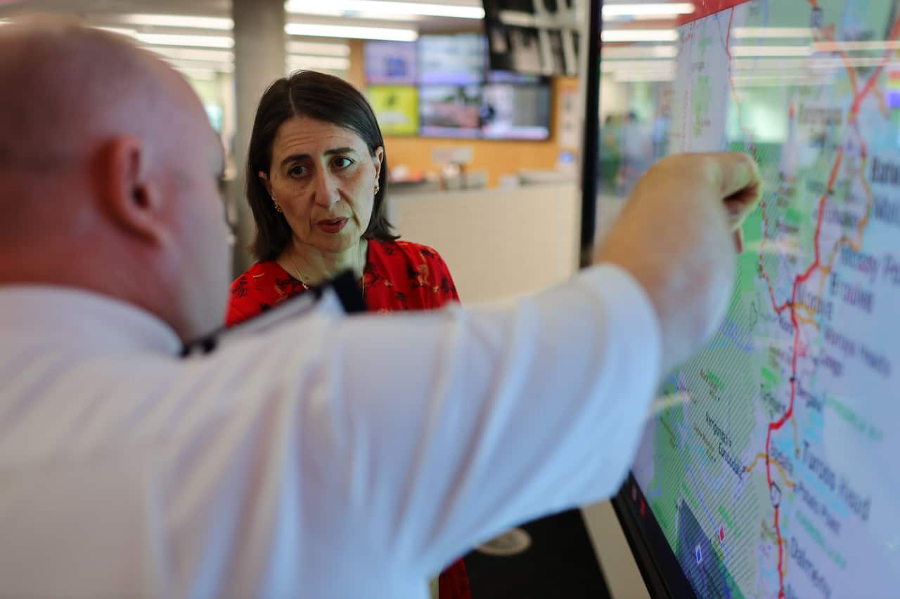 RFS Commissioner Shane Fitzsimmons shows NSW Premier Gladys Berejiklian a map of fire affected areas as part of the recovery operation on Thursday.