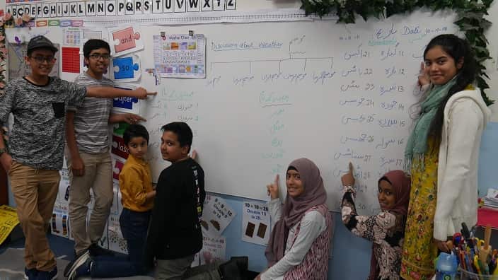 Students pointing to the white board with Urdu words