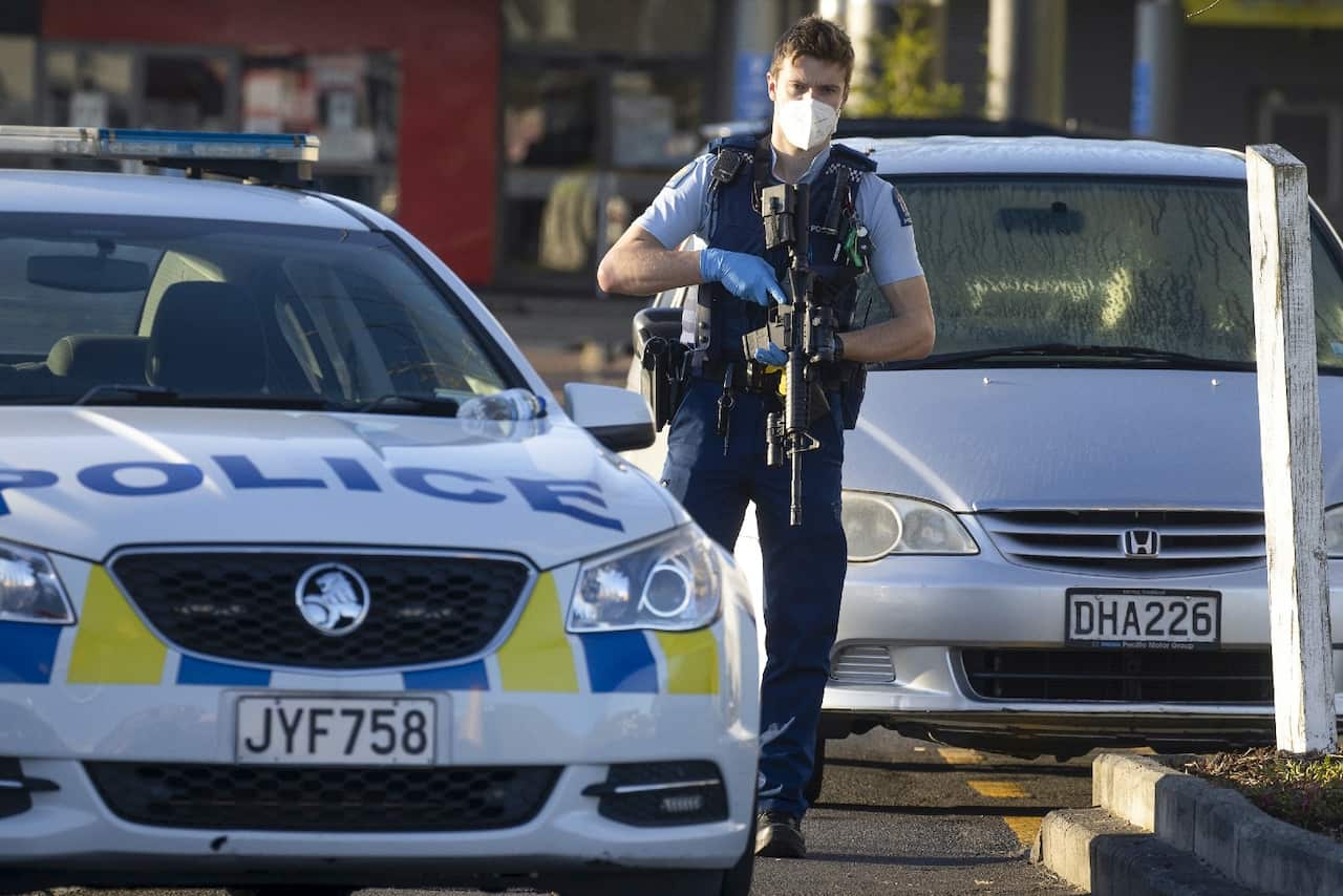 Armed police stand outside a supermarket in Auckland, New Zealand.