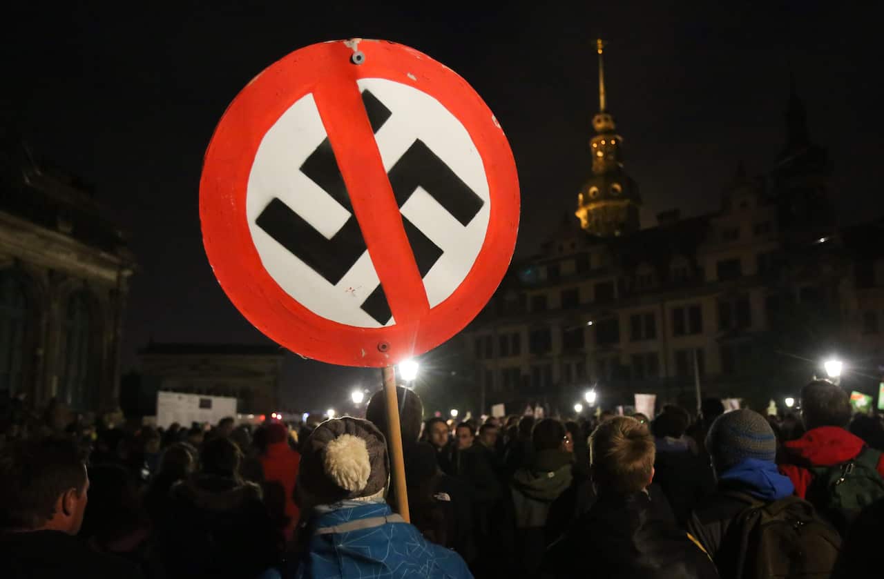Anti-Fascism demonstrators carry a sign with a crossed-out swastika in Dresden, Germany. The Victorian opposition wants to ban the display of Nazi-era symbols.