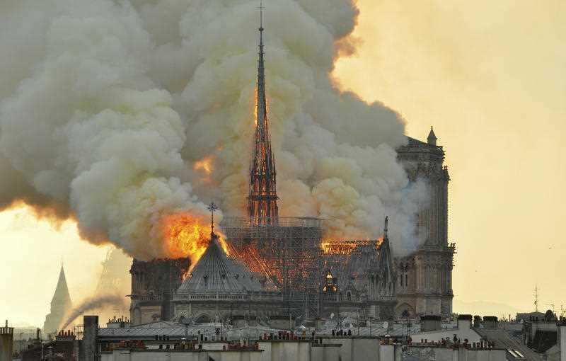 The spire ablaze before it collapsed on Monday.