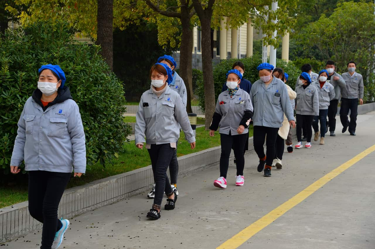 Masked female Chinese workers walk alone and separately for prevention of the novel coronavirus