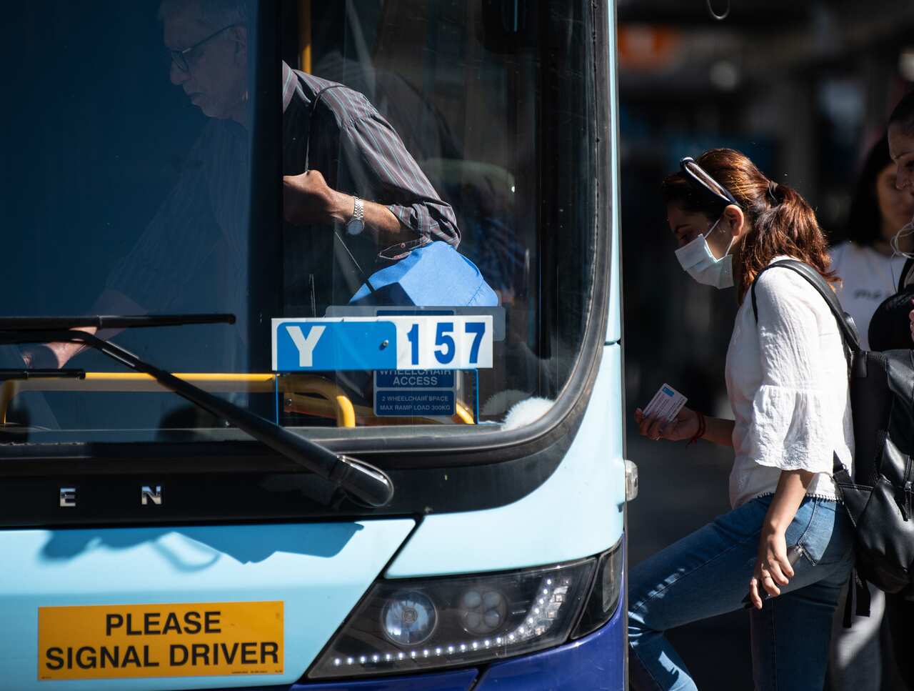 A woman wearing a protective face mask boards a bus in Sydney, Friday, 13 March, 2020. 