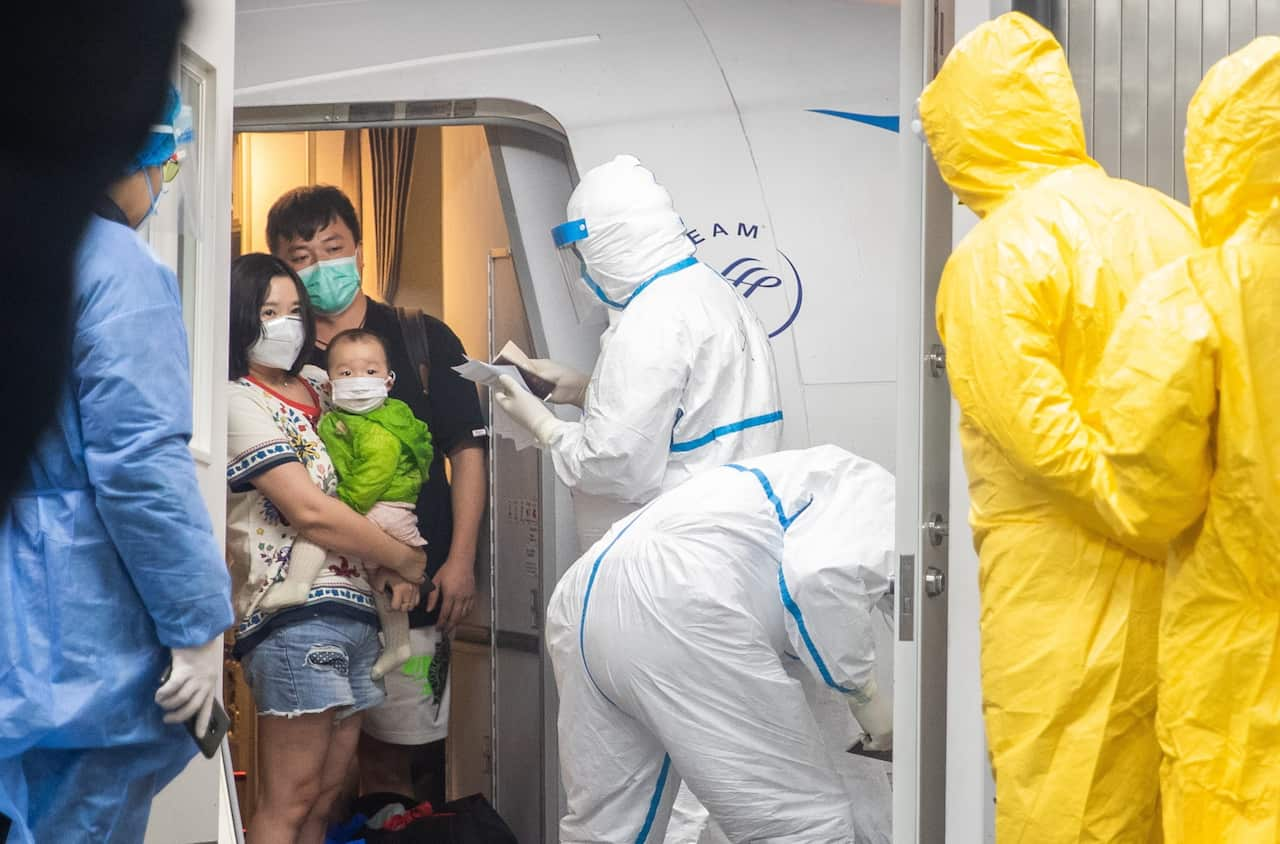 People disembark a chartered Xiamen Airline plane, arrive at Wuhan Tianhe International Airport in Wuhan to be met by medical officials.