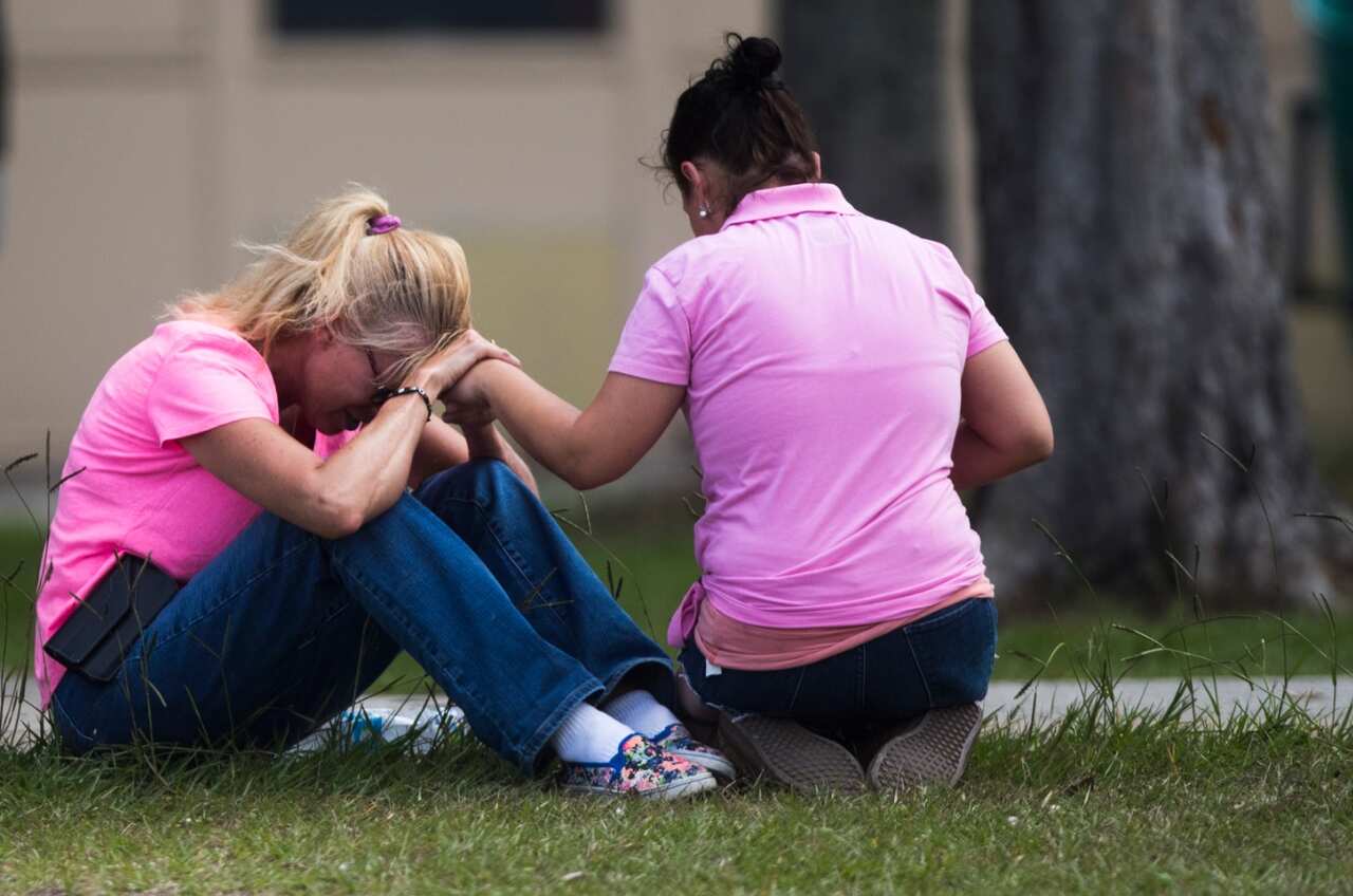 Two women pray outside the family reunification site following a shooting at Santa Fe High School on Friday, May 18, 2018, in Santa Fe, Texas. 