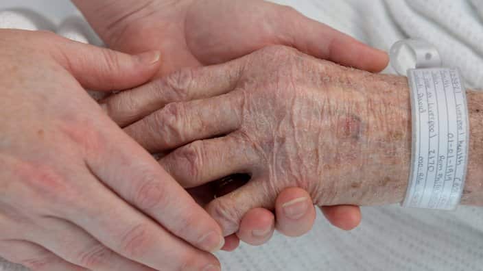 A nurse holds the hand of an elderly patient wearing a hospital identification band at Liverpool Hospital, Sydney on Tuesday, June 11, 2013. (AAP Image/Dan Himbrechts) NO ARCHIVING