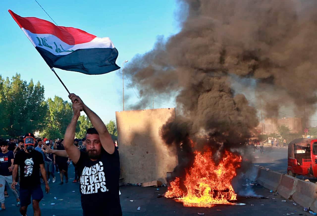 Anti-government protesters set fires and close a street during a demonstration in Baghdad.