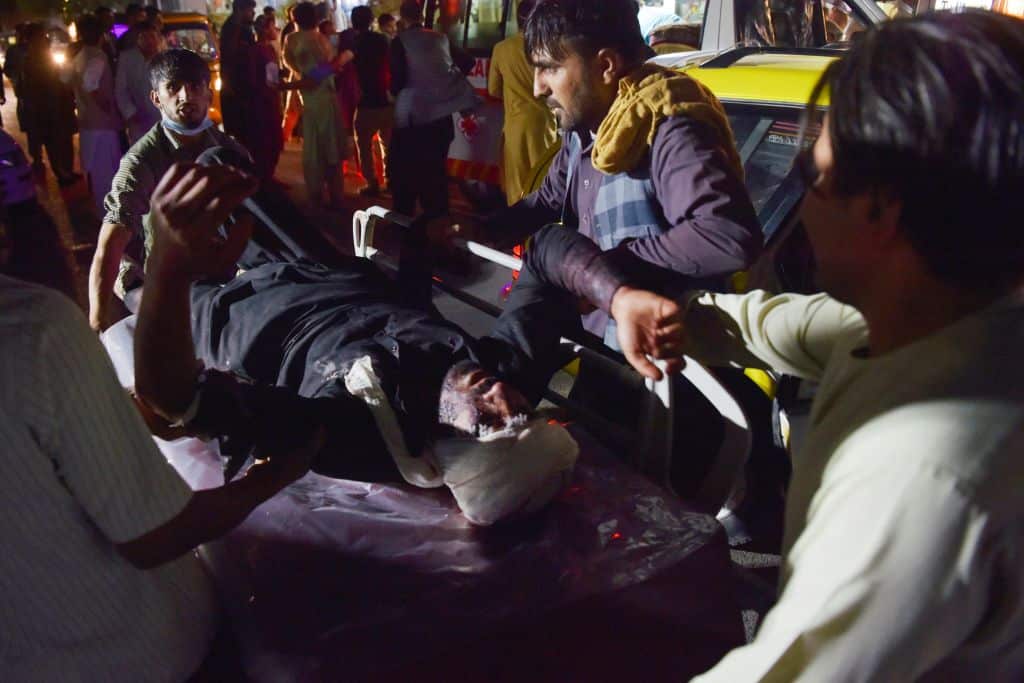 Medical & hospital staff bring an injured man on a stretcher for treatment after 2 blasts, which killed at least five and wounded a dozen, in Kabul on Aug26,21.