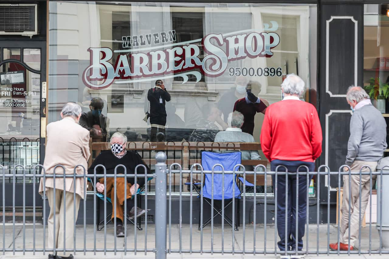 A group of men are seen lined up outside a barbershop as they wait to get their haircut on 19 October, 2020 in Melbourne.