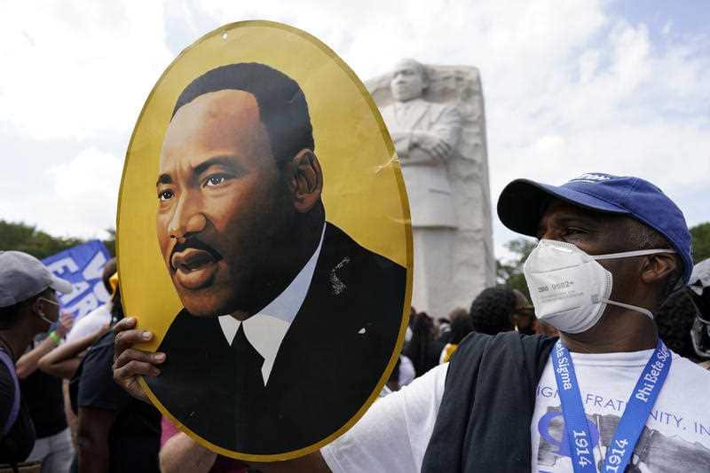A man holds a photo of Martin Luther King, Jr., at the Martin Luther King Jr. Memorial during the March on Washington.