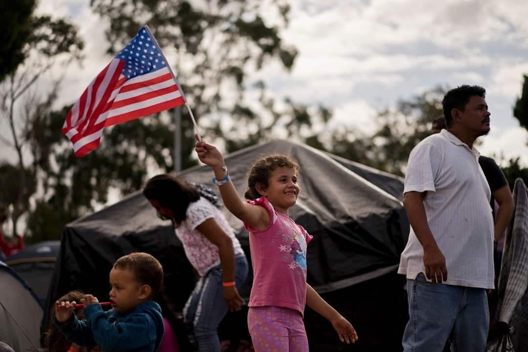 Seven-year-old Honduran migrant Genesis Belen Mejia Flores waves an American flag at a temporary shelter for Central American migrants in Mexico.
