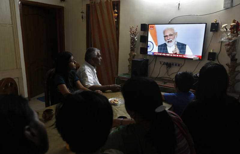 An Indian family watches Indian prime minister Narendra Modi addressing the nation