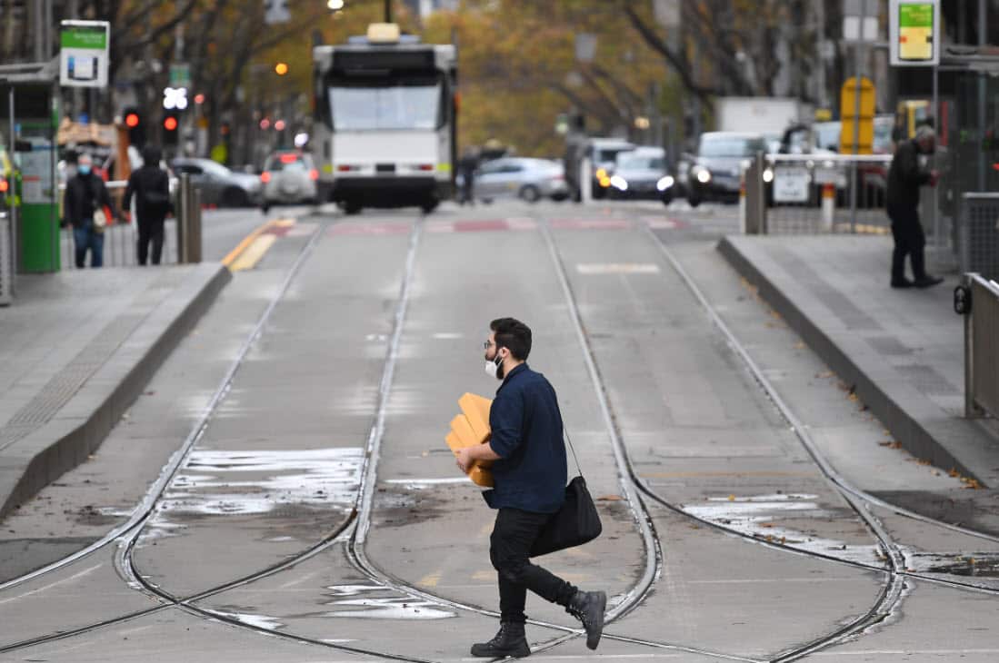 A person wearing a face mask crosses a street in Melbourne, Thursday, May 27, 2021