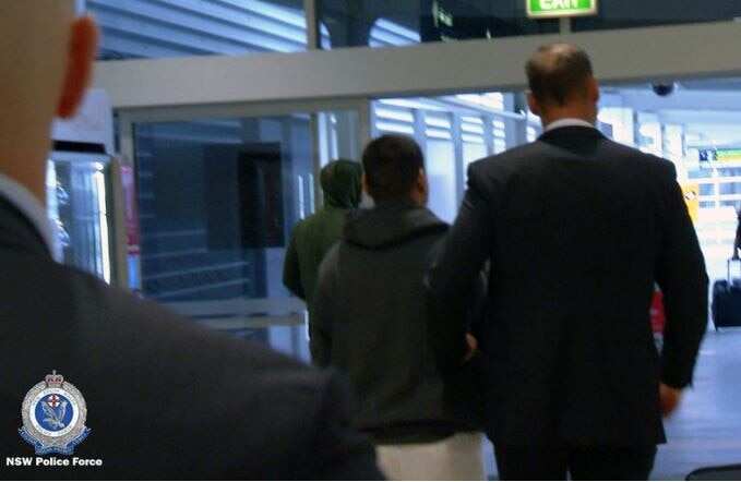 NSW Police Force detectives escort the man through Sydney Airport.