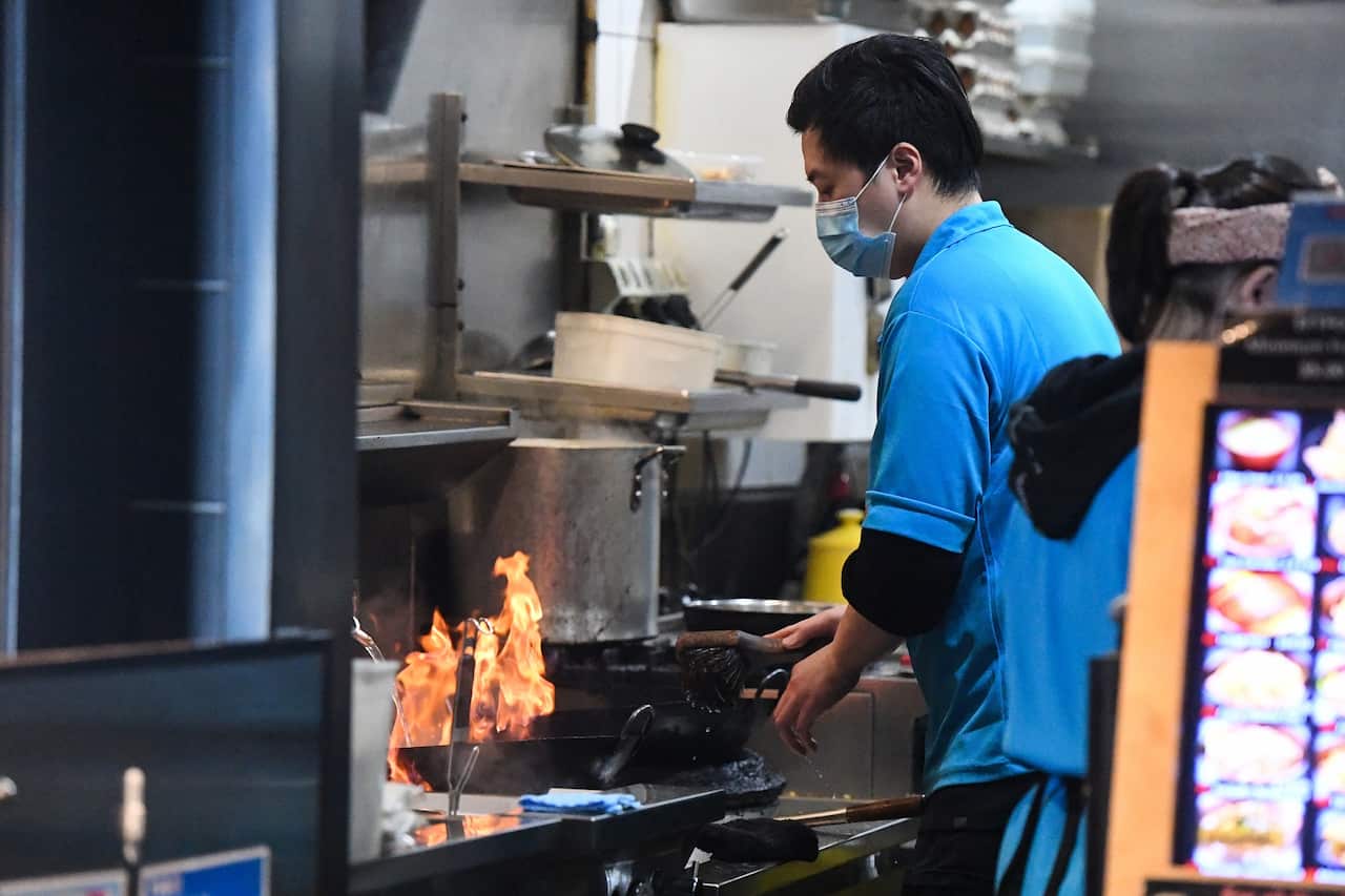 A cook works at a restaurant still open for takeaway in Melbourne 