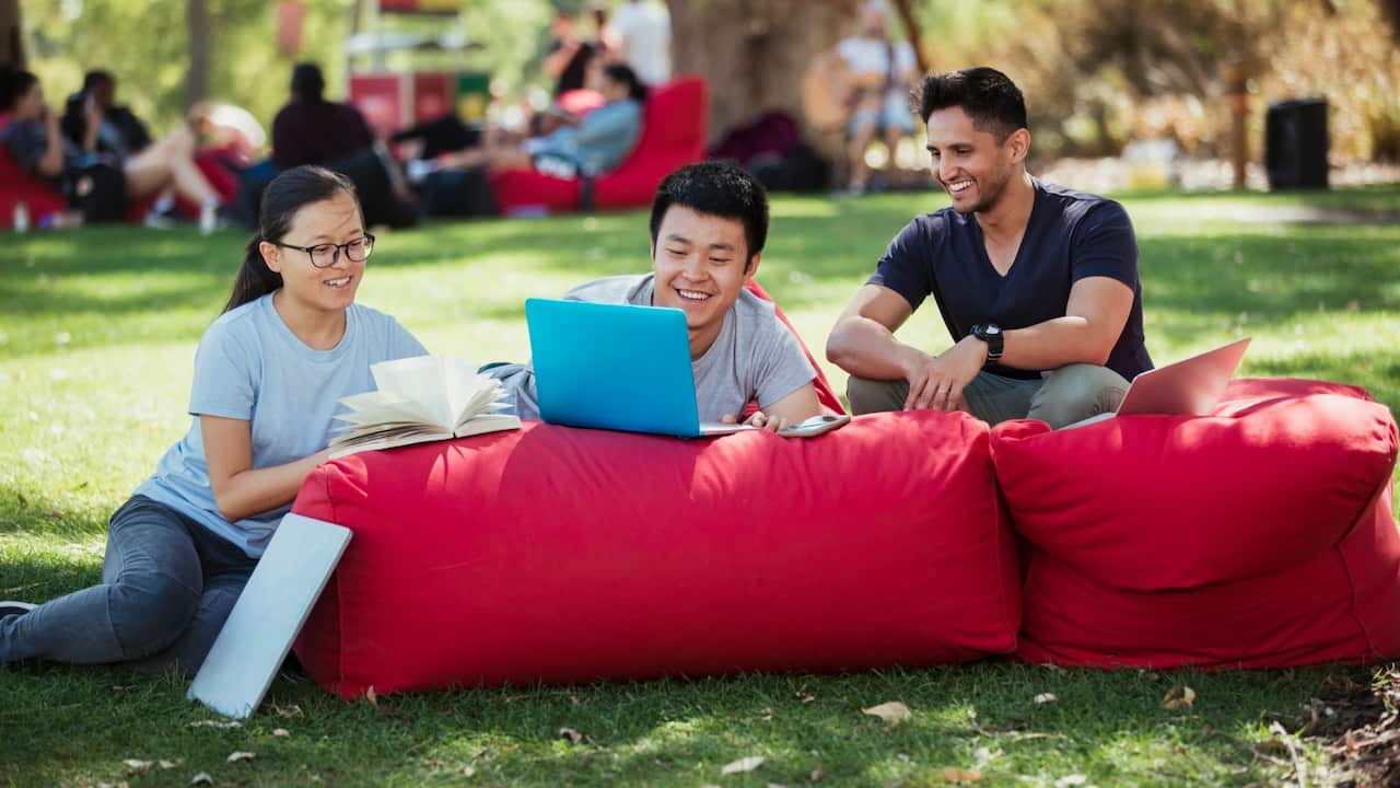 A group of multi ethnic students sitting together on bean bags outdoors on a sunny day in Perth – Getty Images-Solstock
