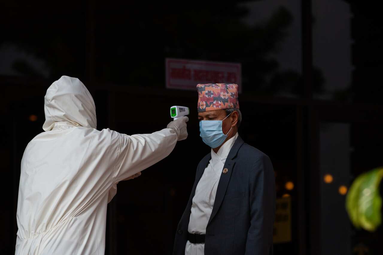 A Nepali health official measures temperature of a member of parliament during covid-19