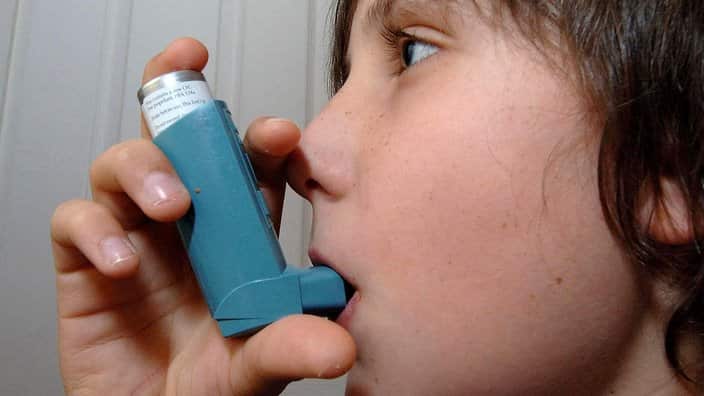 A child using an inhaler for treatment of Asthma. 