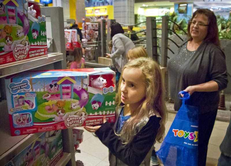 Cinnamon Boffa, right, from Bensalem, Pa., watch as her daughter Serenity pulls a "Chubby Puppies" toy from the shelf at Toys R Us