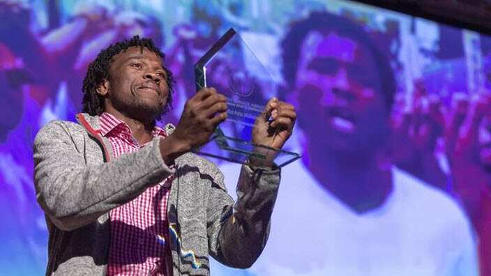 Abdul Aziz Muhamt holding up his 2019 Martin Ennals Award.