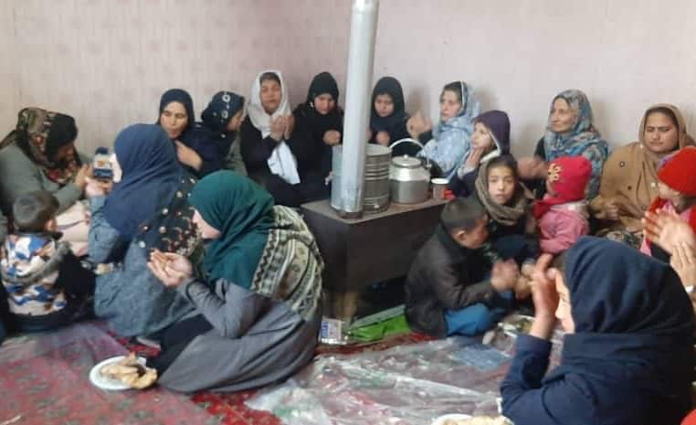Afghan women and children gathered around a heater