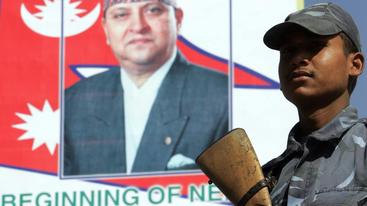 An armed Nepalese policeman stands guard in front of a billboard portraying King Gyanendra with a slogan "Beginning of Nepal's new era" in Kathmandu, 3 Feb 05.