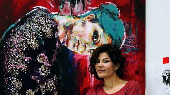 Arya Atti standing in front of her painting