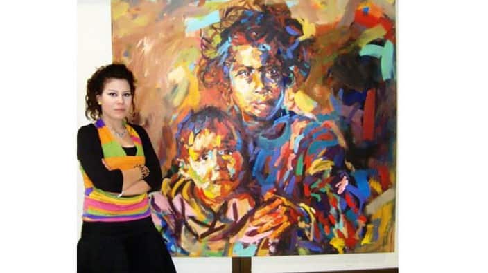 Arya Atta standing next to one of her paintings