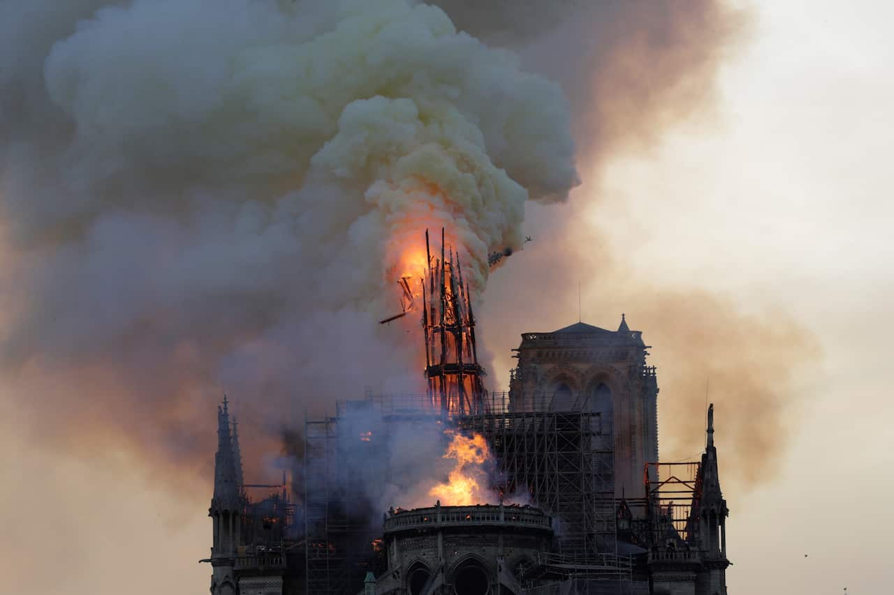 The steeple engulfed in flames collapses as the roof of the Notre-Dame de Paris Cathedral burns on April 15, 2019 in Paris