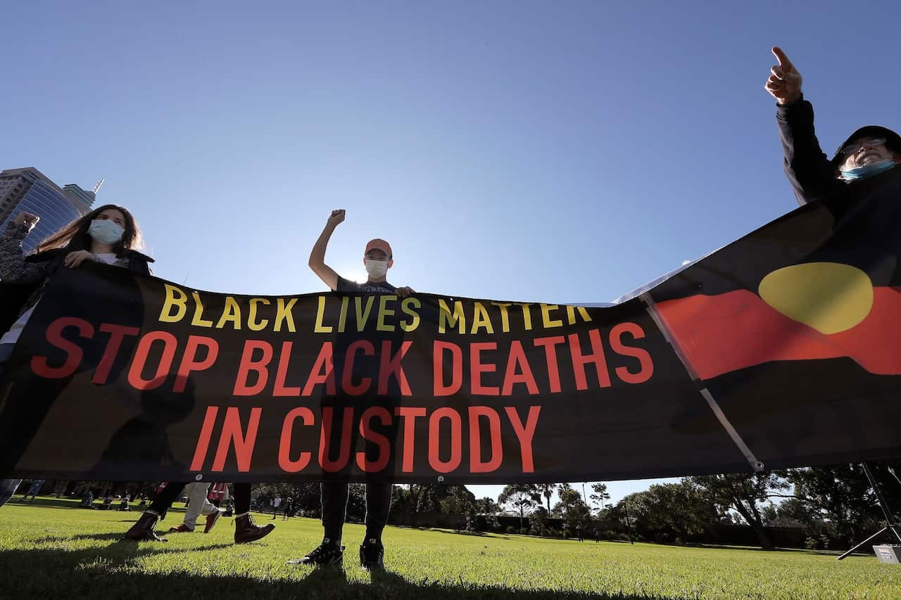 Supporters hold a banner protesting about Black Deaths in Custody at a rally in Sydney on July 5, 2020