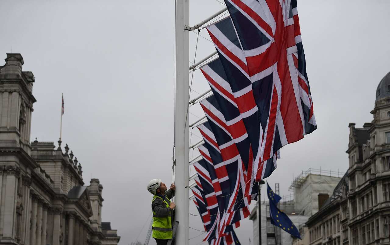 epaselect epa08178581 A man raises Union Flags on Parliament Square in London, Britain, 30 January 2020. After a process that lasted over three years, Britain's withdrawal from the EU is set for midnight CET on 31 January 2020. EPA/NEIL HALL