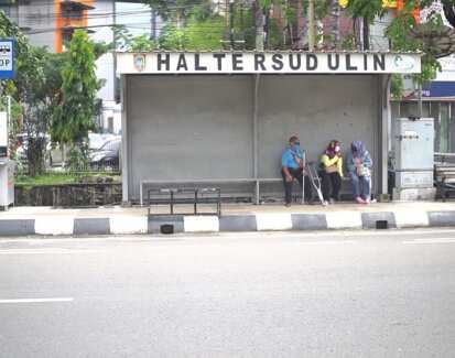 Several people with a disability wait at a bus stop in Banjarmasin.