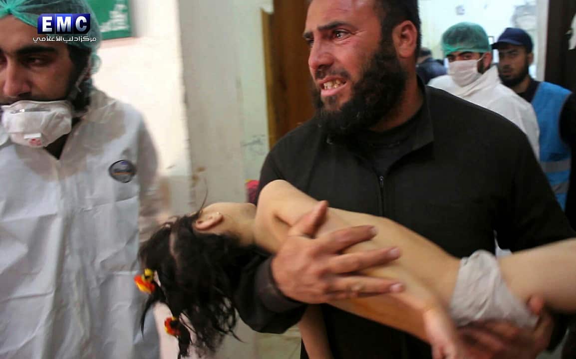 A Syrian man carries a child following a suspected chemical attack, at a makeshift hospital, in Khan Sheikhoun town.