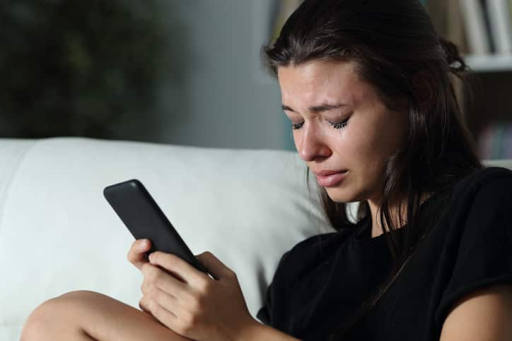 Sad teen crying for help on the phone.