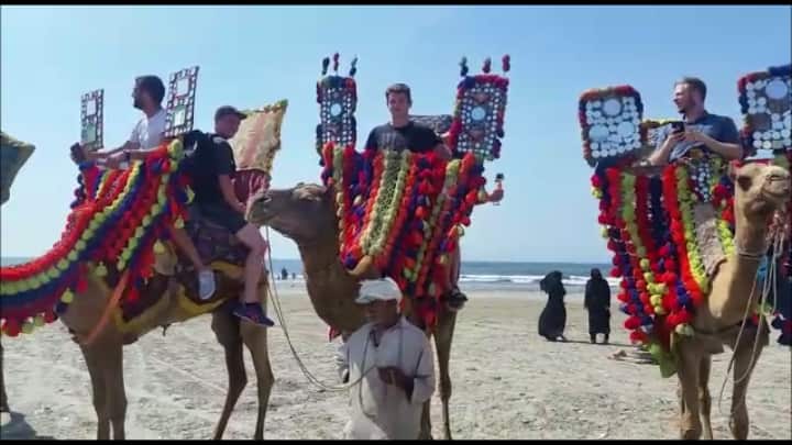 Australian hockey players riding camels on the beack in Karachi, Pakistan