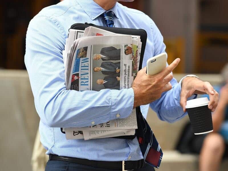 A business man holds a newspaper and coffee
