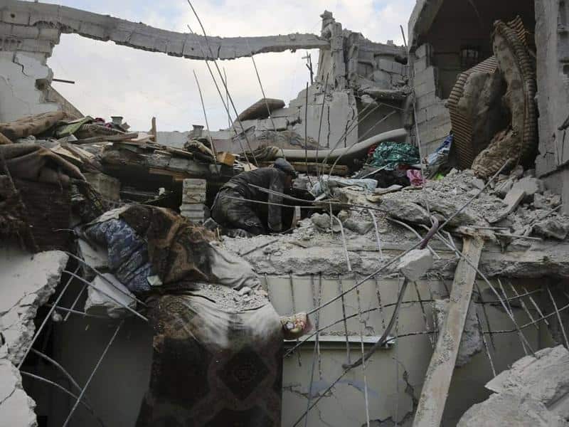 Members of the Syrian Civil Defense group search a destroyed house