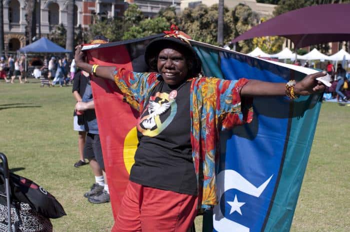 A woman holds the Aboriginal and Torres Strait Island flags at a Survival Day Concert on January 26, 2015.