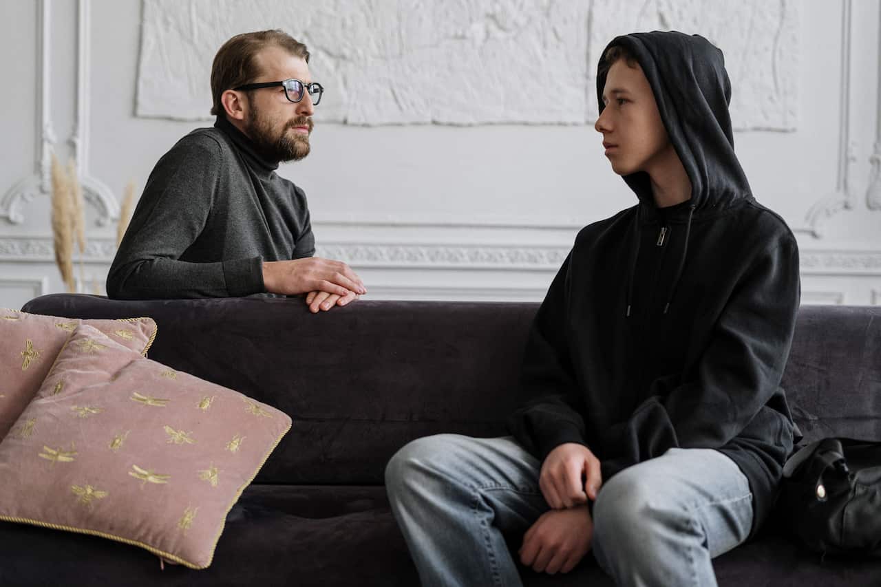 A teenage boy sitting on a sofa with a counsellor