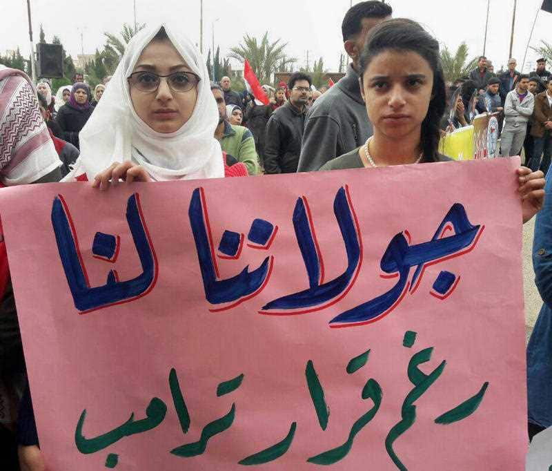 Syrians hold an Arabic banner that reads, "Golan is ours despite Trump's decision," during a protest against President Donald Trump's move.