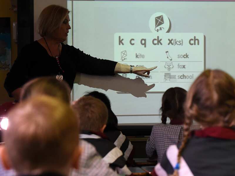 A teacher points at a board during a lesson.