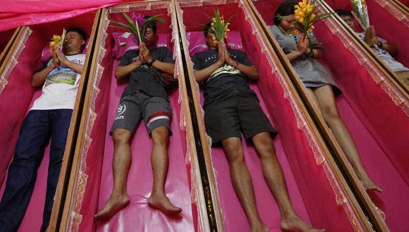 Worshippers pray as they take turns lying in coffins at the Takien temple in suburban Bangkok.