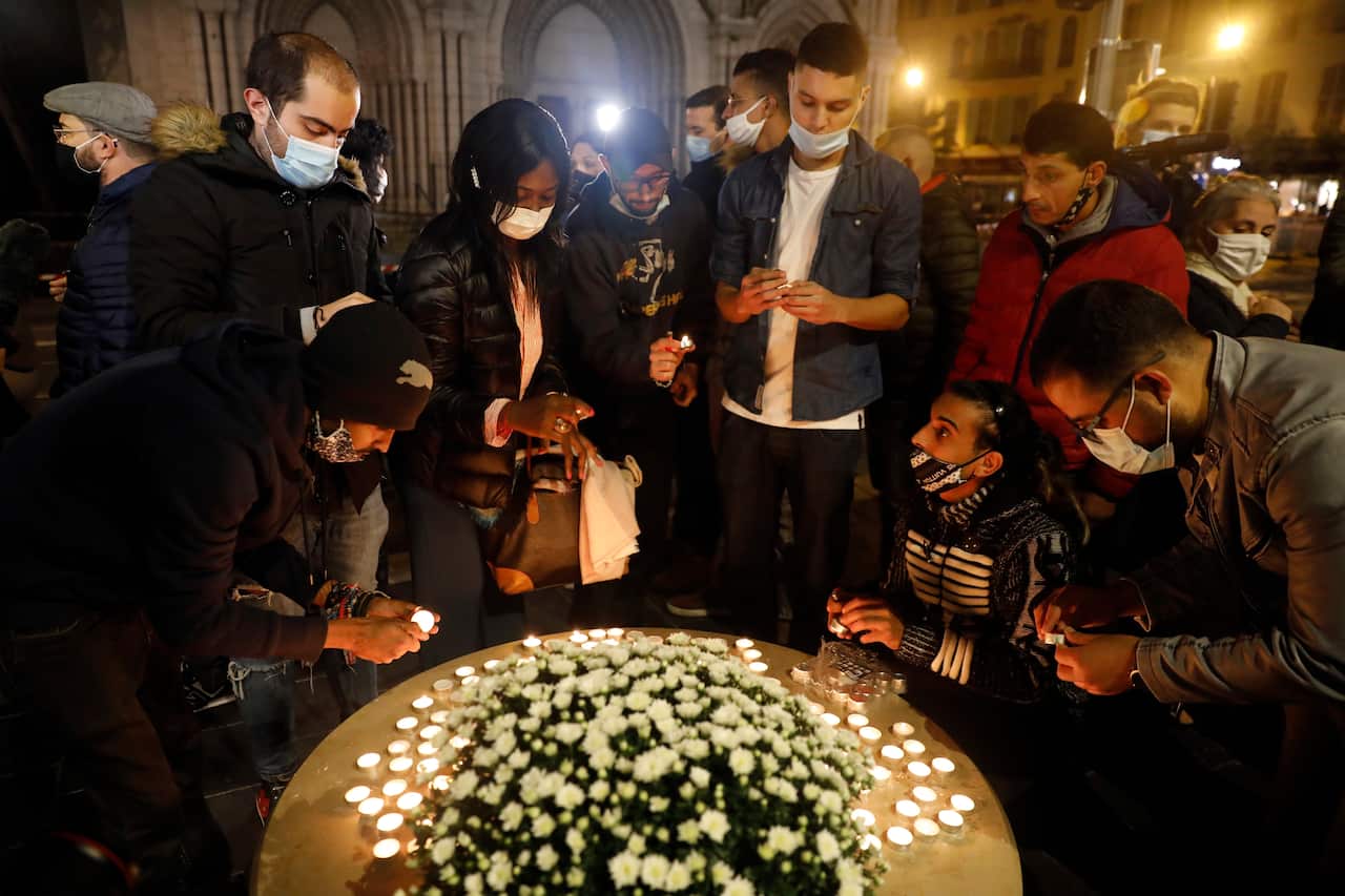 Young people light candles near the entrance of the Notre Dame Basilica church in Nice. 