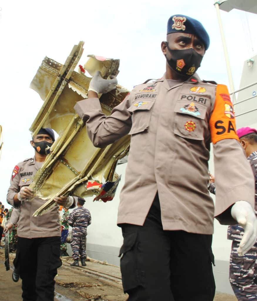 Police carry a piece of debris recovered from the crash site of Sriwijaya Air flight SJ182 at the port in Jakarta.