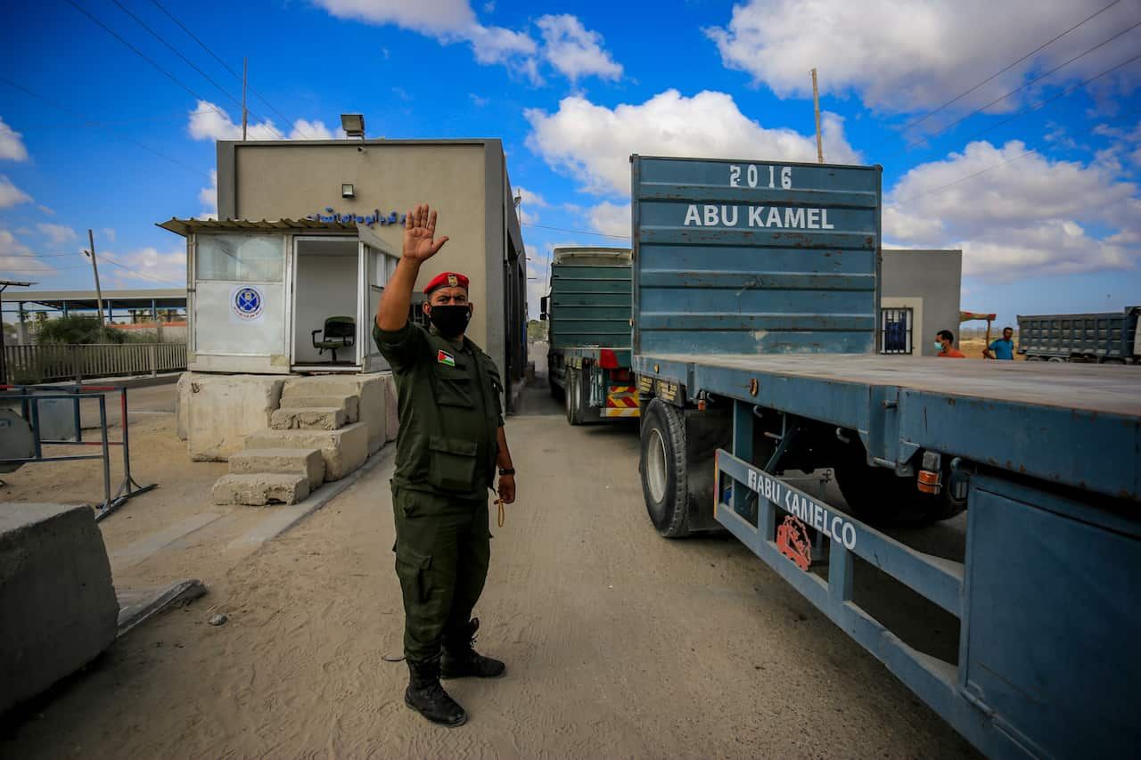 A member of Palestinian Hamas security forces seen wearing a facemask, guides trucks entering the Kerem Shalom crossing