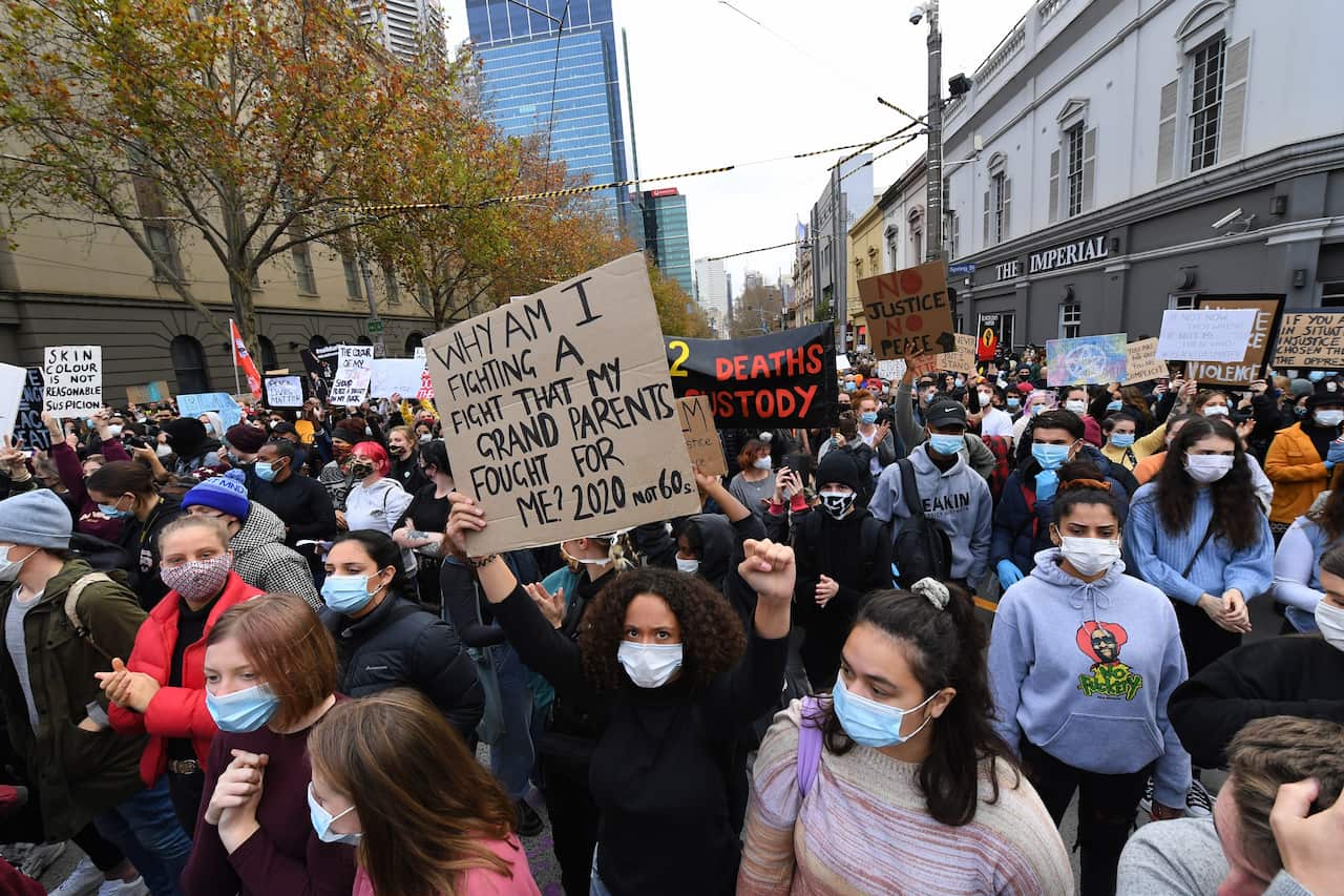 Protesters wearing masks protest against Indigenous deaths in custody.
